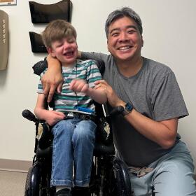 child in wheelchair smiling with doctor